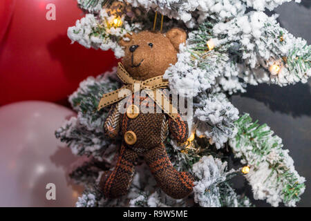 Orso giocattolo in una sciarpa appesa sui rami del Natale Foto Stock