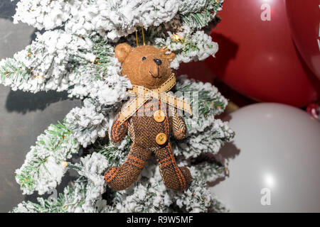 Orso giocattolo in una sciarpa appesa sui rami del Natale Foto Stock