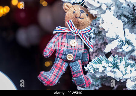 Orso giocattolo in una sciarpa appesa sui rami del Natale Foto Stock