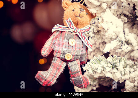 Orso giocattolo in una sciarpa appesa sui rami del Natale Foto Stock