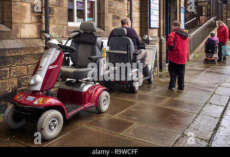 Tre gli scooter di mobilità al di fuori sul marciapiede nel centro di Lancaster, Gran Bretagna del Nord Foto Stock