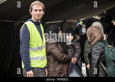 BERKASOVO, SERBIA - Ottobre 17, 2015: ONG volontario in piedi con una famiglia con un bambino in attesa di attraversare la Serbia Croazia confine in Berkasovo Bapska, Foto Stock