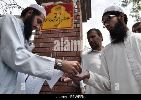 Un uomo distribuisce opuscoli fuori moschea rossa a Islamabad, noto anche come laal masjid prima jummah preghiere. Foto Stock