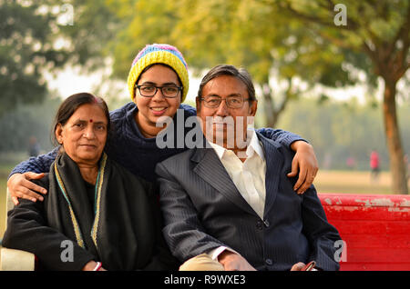 Giovane donna indiana indossando cappello di lana con i suoi genitori che pongono in un parco a Delhi, India Foto Stock