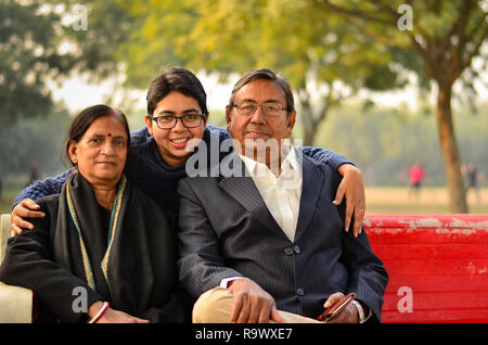 Giovane donna indiana con capelli corti con i suoi genitori che pongono in un parco a Delhi, India Foto Stock