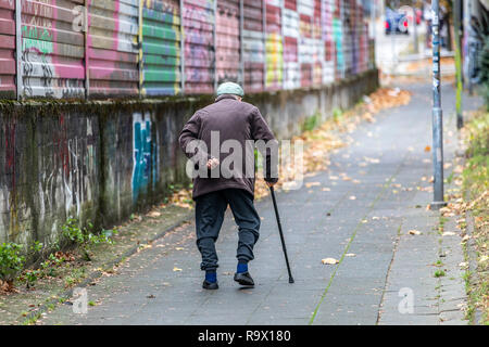 Il vecchio uomo cammina lentamente, appoggiato su un bastone da passeggio, Foto Stock