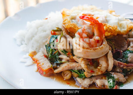 Il riso condito con stir-maiale fritto, calamari, gamberetti, di pollo croccante maiale e basilico e uovo fritto. Foto Stock