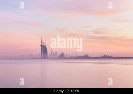 Vista mozzafiato dello skyline di Dubai da Jumeirah Beach al centro illuminato con caldi colori pastello colori sunrise. Dubai, EAU. Foto Stock