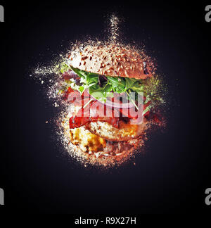 Big burger battenti ed esplosione su sfondo nero Foto Stock