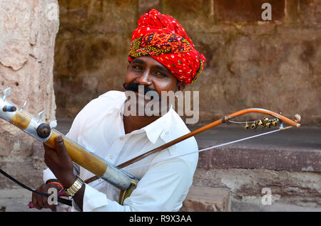 Jodhpur, Rajasthan, India, 2019. Rajasthani tradizionale sarangi player nel suo abito tradizionale e la testa dentata turbante rosso pagdi giocando sarangi. Foto Stock