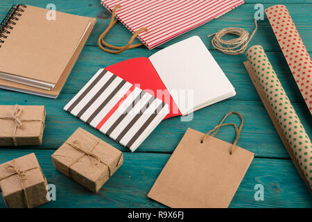 Festeggiamenti e concetto di istruzione - set di striping fatti a mano shopping bag, buste regalo, carta da imballo con la polka dots, taccuini su blu backgrou in legno Foto Stock