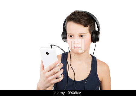 E adolescenti concetto tecnologico. Giovane ragazzo in stile casual con cuffie ascoltando la musica dal suo smartphone isolato su bianco Foto Stock