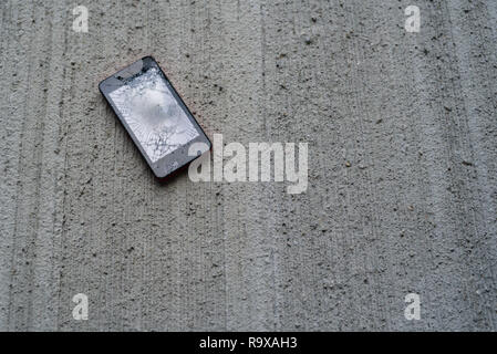 Telefono con schermo rotto su calcestruzzo sfondi Foto Stock