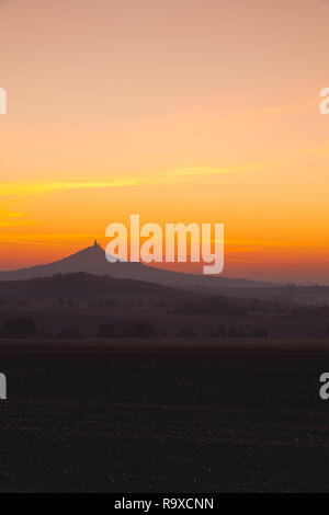 La silhouette di Hazmburk castello presso sunrise.Central Bohemian Uplands,Repubblica Ceca. Nella parte superiore della montagna vi è la rovina di un cast medievale Foto Stock