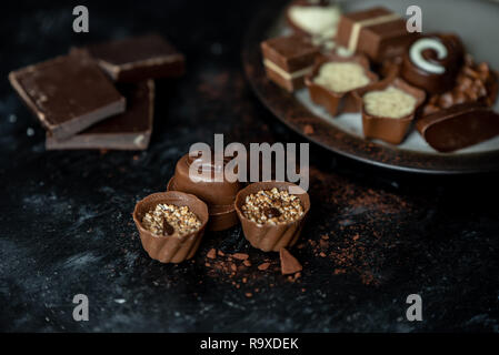 Diversi, dolci praline di cioccolato fondente, al latte e bianco su di un legno scuro dello sfondo Foto Stock