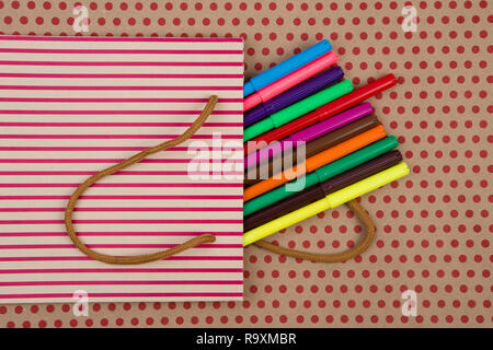 Istruzione e concetto celebrativo - handmade striped shopping bag, buste regalo, accessori da scrivania, colorati pennarelli sulle imbarcazioni di sfondo della carta in re Foto Stock