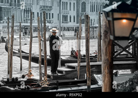Gondoliero indossando cappello di paglia sorge sul molo. Grand Canal, Venezia Foto Stock