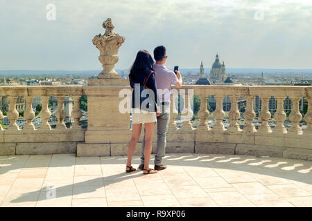 Coppia giovane di etnia asiatica sta rendendo selfie sulla Royal Palace terrace contro vista di Budapest Foto Stock