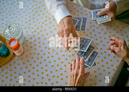 Coppia di anziani divertirsi giocando a carte insieme al tavolo della cucina. Foto Stock