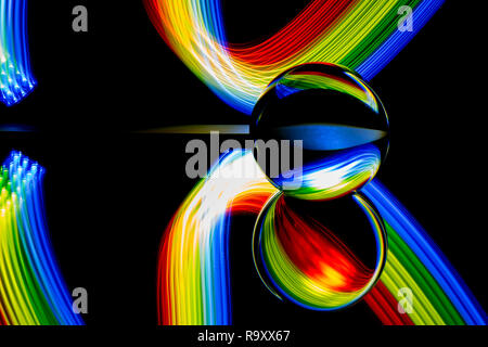 La pittura di luce con una lente a sfera/sfera di cristallo / Vetro / a sfera con sfera colorata a strisce blu riflessioni sulla superficie nera. strisce di turbolenza. Foto Stock