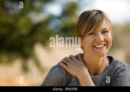 Ritratto di un sorridente giovane donna fuori in giardino. Foto Stock