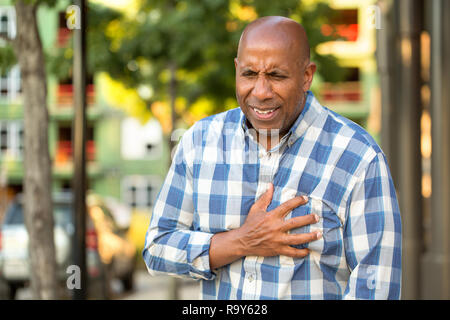 African American Man aventi i dolori tenendo il suo petto. Foto Stock