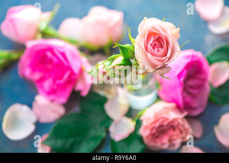 Bottiglie di vetro con rosa peonia rosa su sfondo chiaro con copia spazio. Intestazione femminile con petali e fiori in toni pastello Foto Stock
