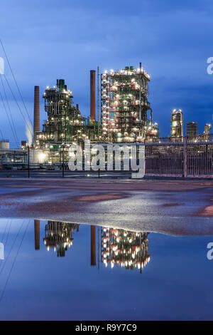 Illuminata produzione petrolchimica impianto al crepuscolo con drammatica nuvole riflettono in uno stagno, porto di Anversa, Belgio. Foto Stock