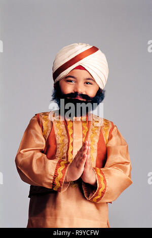 Giovane ragazzo Sikh vestito come un adulto con un falso di baffi e barba in costume tradizionale, Foto Stock