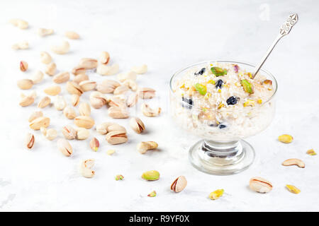 Indian Kheer dessert dal riso, frutta secca e spezie nel gelato ciotola su marmo bianco tabella Foto Stock