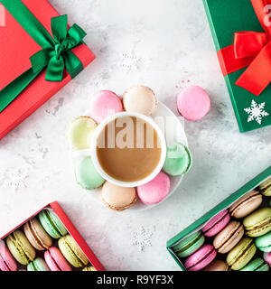 Colorati macarons francese con la tazza di caffè e presenti caselle di Natale su sfondo bianco Foto Stock