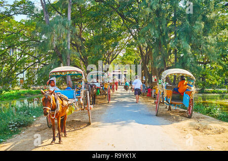 AVA, MYANMAR - Febbraio 21, 2018: loschi strada tra due serbatoi di acqua è occupata con carrelli a cavalli, weiting i turisti che giungono qua per visi Foto Stock