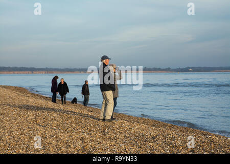 Per coloro che godono di una passeggiata invernale sulla spiaggia in Hampshire, Regno Unito. Tempo libero, visitatori dog walkers, guardando al mare Foto Stock