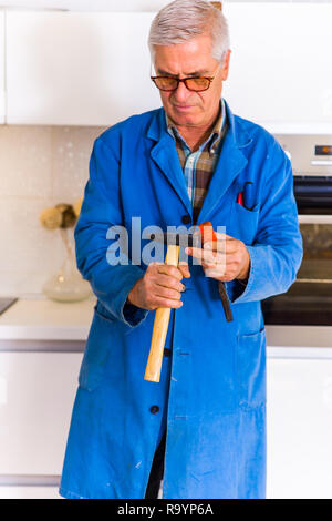 Una vecchiaia tuttofare in generale è in piedi in cucina con i suoi attrezzi Foto Stock