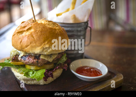 Burger gourmet con un lato di Ketchep e le patatine fritte in un cestello. Servita in un ristorante in stile occidentale in Asia. Foto Stock