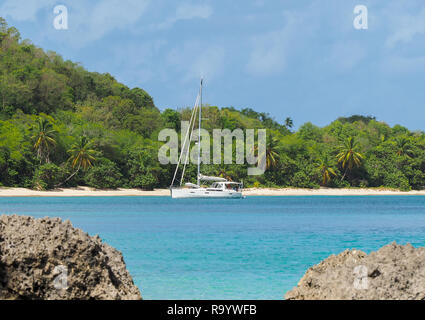 Catamarano ormeggiato nel porto di Marie Galante Bay, la spiaggia tropicale in background e mare turchese Foto Stock