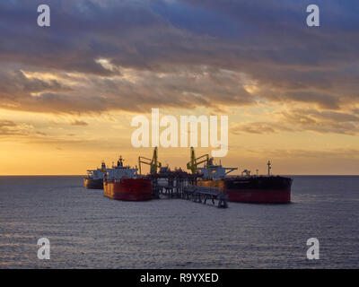 Diverse le petroliere di olio di scarico di prodotti a un molo Offshore all'ancoraggio della Freeport nelle Bahamas su uno mattina all'alba, dei Caraibi. Foto Stock