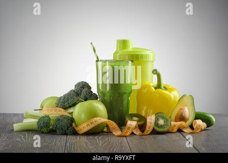 Cime di broccoli, avocado, Apple, peperone, sedano, cetriolo, kiwi, shaker e bicchiere di frullato. Dieta vegana per perdere peso. Foto Stock