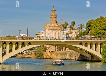 Siviglia Spagna la Torre del Oro o Torre del Oro sulle rive del fiume Guadalquivir e nave passeggeri passando sotto il ponte TELMO Foto Stock