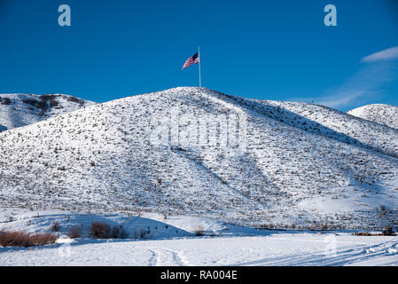 Bandiera americana onde orgogliosamente su un pendio nevoso. Foto Stock