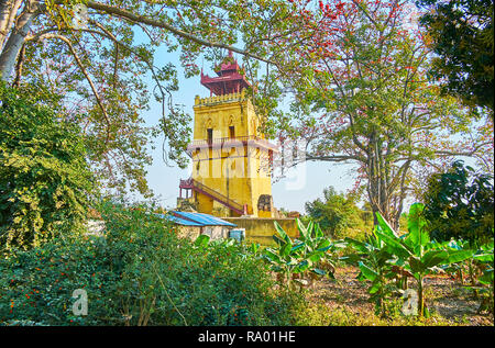 La vista sul Nanmyin medievale torre di avvistamento attraverso la boscaglia di giardino tropicale con cotton tree, banana palme e altre piante locali, Ava, Myanmar. Foto Stock