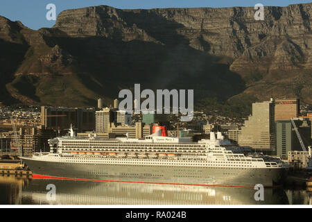 La Queen Mary 2 ormeggiata in Cape Town Harbour con riflesso nell'acqua e Table Mountain dietro. Foto Stock