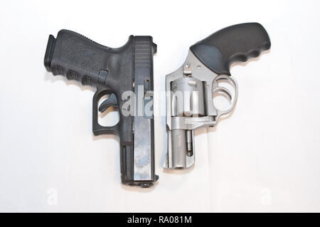 Due pistole, un nero 9mm pistola ed un argento 357 revolver Magnum, caricato con oro punto cava pallottole affiancate su uno sfondo bianco Foto Stock