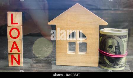 Miniatura casa in legno, dollari e l'iscrizione ' ' di prestito. Acquisto di una casa in debito. Famiglia gli investimenti in proprietà immobiliari e la gestione del rischio concetto. Loa Foto Stock