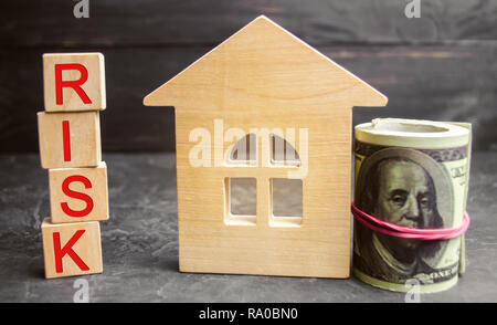 Miniatura casa in legno, dollari e l'iscrizione ' rischio'. Acquisto di una casa, un appartamento e rischi finanziari. Perdita di proprietà per il mancato pagamento. Prop Foto Stock