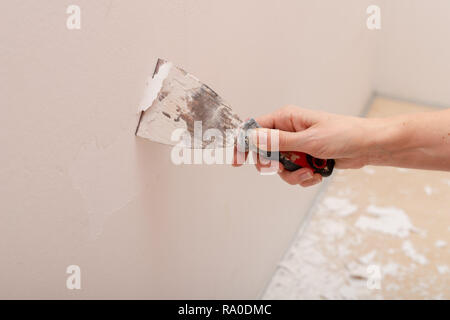 Spelatura di vecchia vernice dalla parete. Il rinnovamento e la verniciatura delle pareti nell'appartamento. Luogo - home farm. Foto Stock