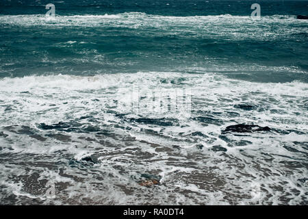 Bellissimo mare scuro in superficie ruvida meteo, onde schiumose rotolare sulla spiaggia sabbiosa. Foto Stock