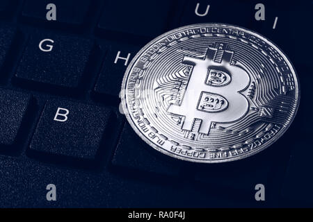 Bitcoin sulla tastiera compuer in background, simbolo di elettronici di denaro virtuale e data mining cryptocurrency concetto. Coin moneta crypto bitcoin giace sul Foto Stock