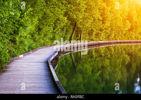 Passerella in legno intorno al lago di Bled con le montagne e le case sullo sfondo. Bellissima natura slovena. Bled, Slovenia, l'Europa. Foto Stock