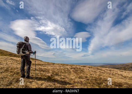 Femmina solitario escursionista fissando in un grande cielo blu con nuvole a lunga distanza. Prese su Moel Eilio, Snowdonia, Galles. Foto Stock